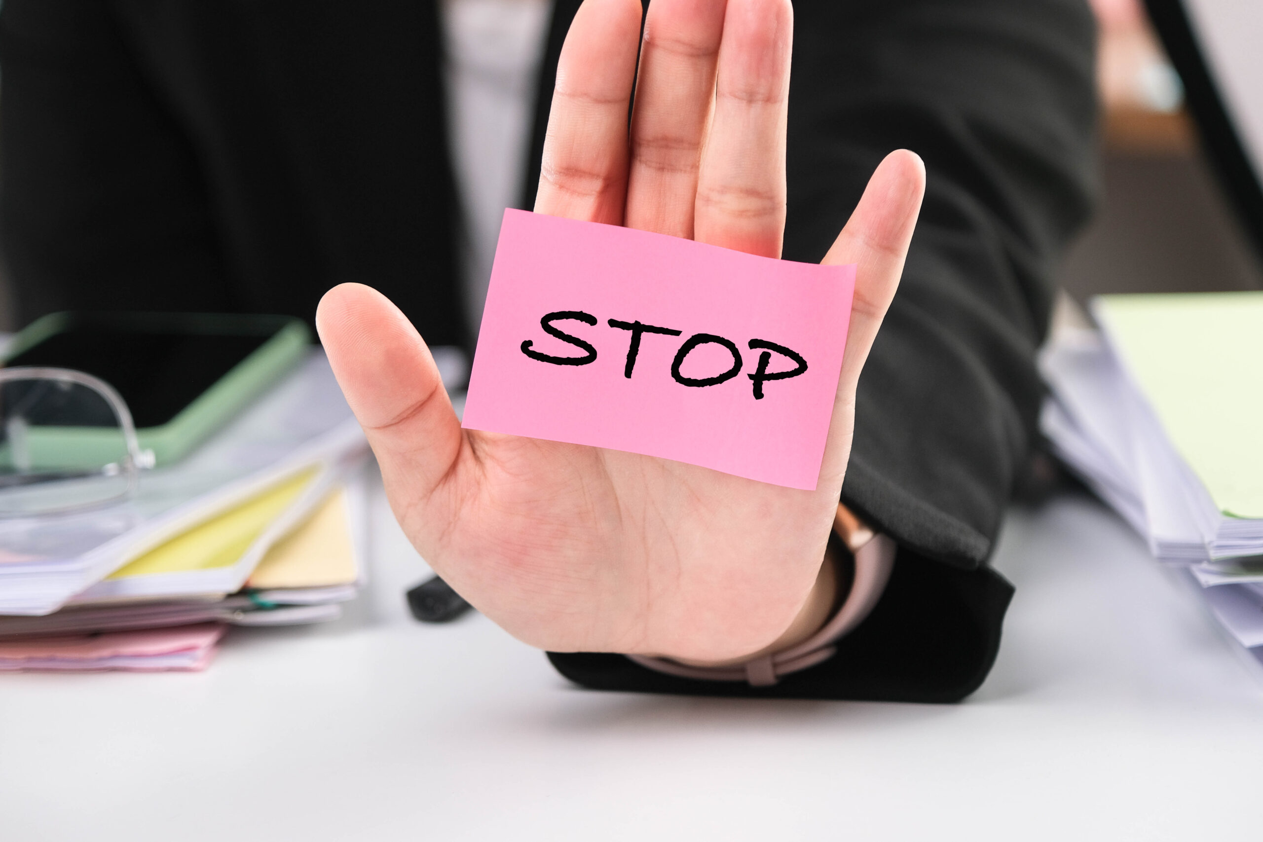 Close-up of a business woman showing a stop gesture with the inscription "Stop" on her palm. Stop corruption concept.